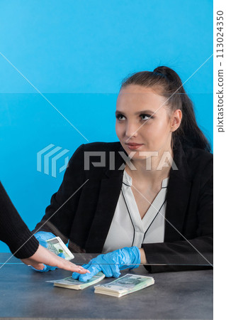 The young cashier put on latex gloves to increase safety during the ongoing coronovirus outbreak. The young cashier put on latex gloves to increase safety during the ongoing coronovirus outbreak. 113024350