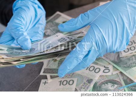 Hands of young cashier in protective gloves hand over bundles of banknotes. Hands of young cashier in protective gloves hand over bundles of banknotes. 113024366