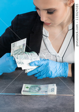 A young intern at a bank counts cash at her cashier desk. 113024385