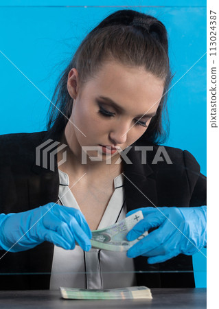 A young intern at a bank counts cash at her cashier desk. A young intern at a bank counts cash at her cashier desk. 113024387