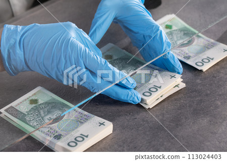 Hands of young cashier in protective gloves hand over bundles of banknotes. Hands of young cashier in protective gloves hand over bundles of banknotes. 113024403