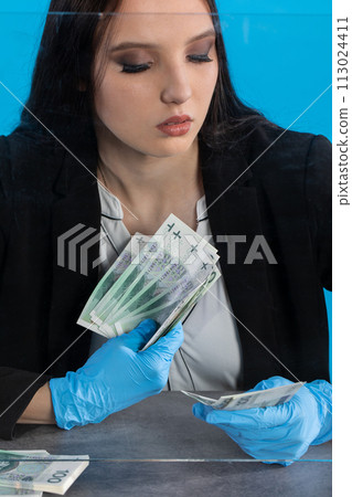 A young intern at a bank counts cash at her cashier desk. A young intern at a bank counts cash at her cashier desk. 113024411