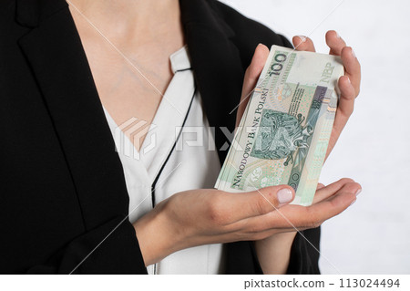 The woman is showing a large bundle of banknotes, holding gently in her hands. The woman is showing a large bundle of banknotes, holding gently in her hands. 113024494
