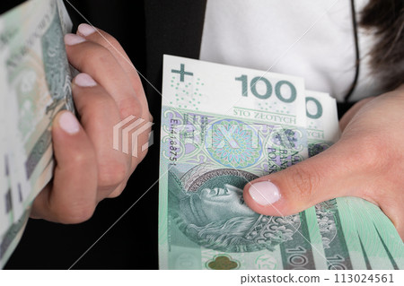 The woman is counting exactly one hundred zlotys paper banknotes. 113024561