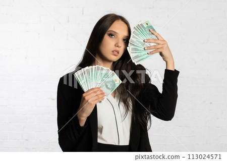 Businesswoman holds Polish banknotes in a fan-shaped hands. 113024571