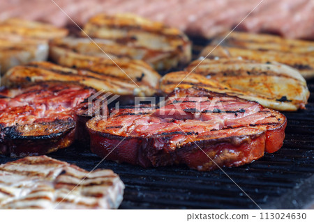 Roasted pork knuckle, chicken breast, and traditional Romanian mititei on the grill, from close-up, focus on pork knuckle 113024630