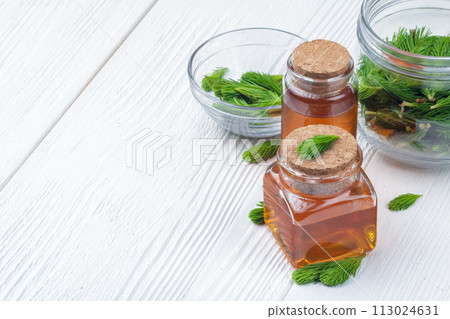 Homemade pine cough syrup for dry irritating throat coughs. Made from green young pine buds and honey.Alternative medicine concept on white wooden table (selective focus). 113024631