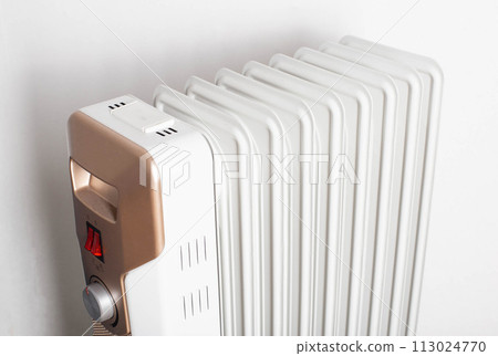 Modern electric oil heater on a white background. Heating the room. Heating season in apartments, close-up 113024770