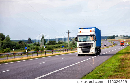A container truck with a semi-trailer transports cargo from a port to another country along the highway in the summer, merchandise 113024829