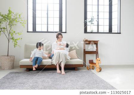While feeding the baby on the sofa in the bright living room While feeding the baby on the sofa in the bright living room 113025017