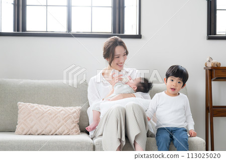 While feeding the baby on the sofa in the bright living room 113025020