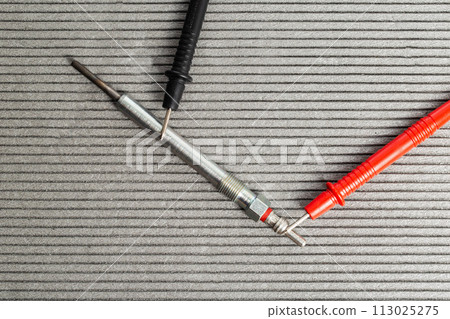 Checking the serviceability of the glow plug with a multimeter. Glow plug voltage resistance. Modern heating element, close-up 113025275