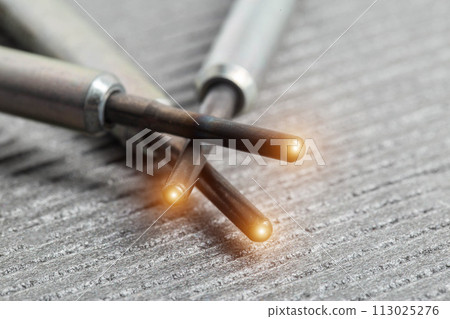 Serviceable modern ceramic glow plugs on a gray background. Orange glow, heating element. Pre-heating of a diesel engine, close-up Serviceable modern ceramic glow plugs on a gray background. Orange glow, heating element. Pre-heating of a diesel engine, close-up 113025276