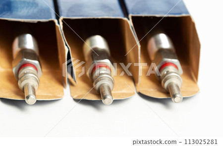 New modern ceramic glow plugs in packaging on a white background. Concept for replacing glow plugs in cold weather, close-up. Automotive part New modern ceramic glow plugs in packaging on a white background. Concept for replacing glow plugs in cold weather, close-up. Automotive part 113025281