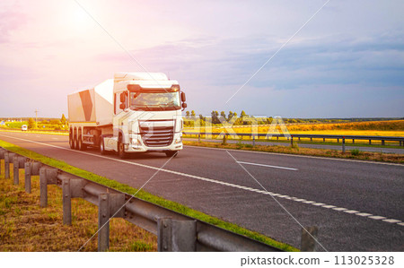 A new modern semi-trailer glass truck transports fragile cargo in the form of glass and mirrors along the highway against the backdrop of sunset. Copy space for text 113025328