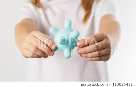 A blonde girl holds a model of a virus in her hands. Concept of infectious diseases in children, polio and whooping cough, close-up 113025451
