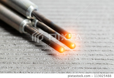 Serviceable modern ceramic glow plugs on a gray background. Orange glow, heating element. Pre-heating of a diesel engine, close-up Serviceable modern ceramic glow plugs on a gray background. Orange glow, heating element. Pre-heating of a diesel engine, close-up 113025488