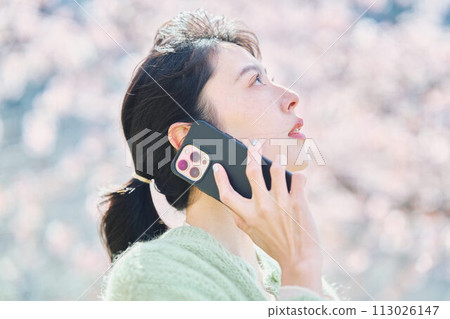 A woman talking on a smartphone under the cherry blossoms 113026147