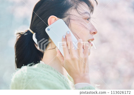 A woman talking on a smartphone under the cherry blossoms 113026172