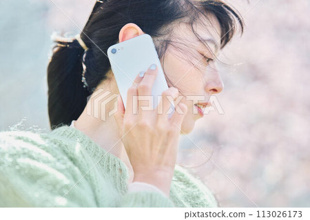 櫻花下用智慧型手機說話的女人 113026173