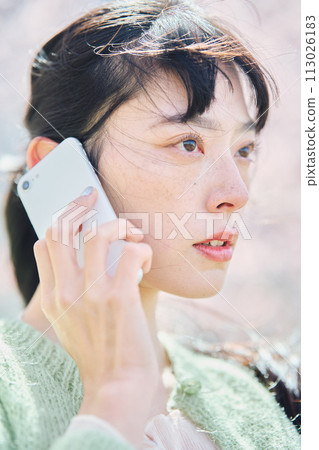 A woman talking on a smartphone under the cherry blossoms 113026183
