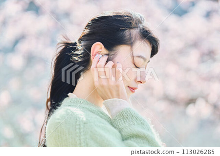 A woman listening to music among cherry blossoms 113026285