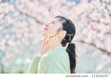 A woman listening to music among cherry blossoms A woman listening to music among cherry blossoms 113026297