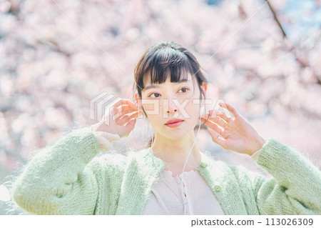 A woman listening to music among cherry blossoms A woman listening to music among cherry blossoms 113026309
