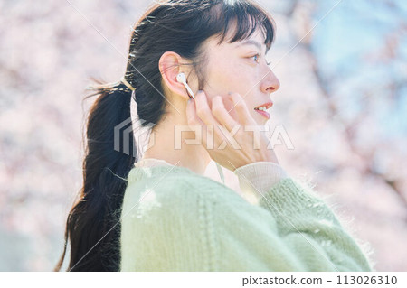 A woman listening to music among cherry blossoms 113026310