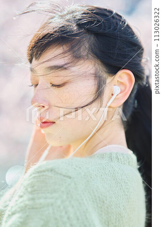 A woman listening to music among cherry blossoms A woman listening to music among cherry blossoms 113026322