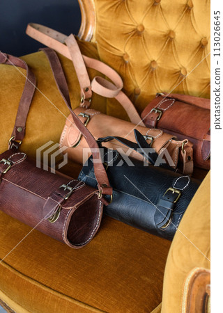 Old vintage leather tube shape bags with leather strap. Beautiful small women's leather bags in a vintage velor chair Old vintage leather tube shape bags with leather strap. Beautiful small women's leather bags in a vintage velor chair 113026645