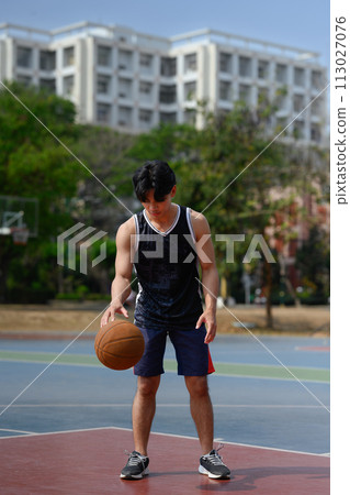 Full length portrait of sportsman playing basketball on court during a sunny day Full length portrait of sportsman playing basketball on court during a sunny day 113027076