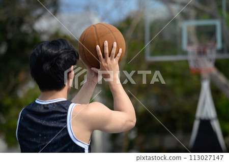Back view of young basketball player throwing the ball to the basket at outdoor court Back view of young basketball player throwing the ball to the basket at outdoor court 113027147