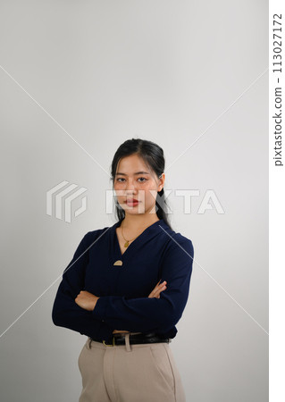 Attractive businesswoman standing with arms crossed and looking at camera confidently 113027172
