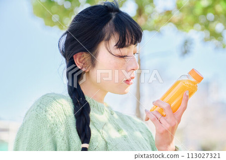 一個女人在新鮮的綠色公園裡喝著柳橙汁 113027321