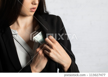 The businesswoman hides the money behind her bosom into the inside pocket of the coat. 113027477