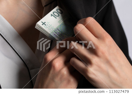 The businesswoman hides the money behind her bosom into the inside pocket of the coat. 113027479