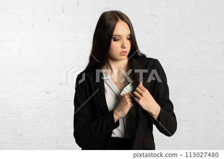 The businesswoman hides the money behind her bosom into the inside pocket of the coat. 113027480
