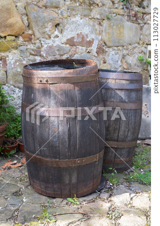 Old wooden barrels in garden on stones wall Old wooden barrels in garden on stones wall 113027729