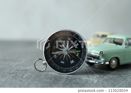 A compass on a table with a car. 113028034