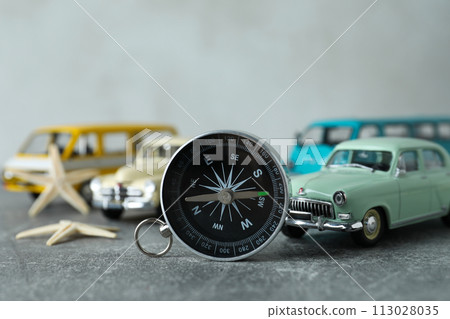 A compass on a table with a car. 113028035