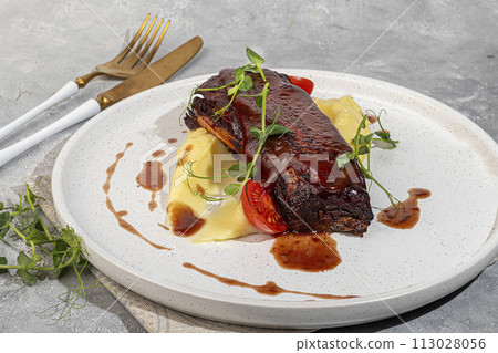 Beef on the bone with mashed potatoes, topped with red sauce and cherry tomatoes. Beef on the bone with mashed potatoes, topped with red sauce and cherry tomatoes. 113028056