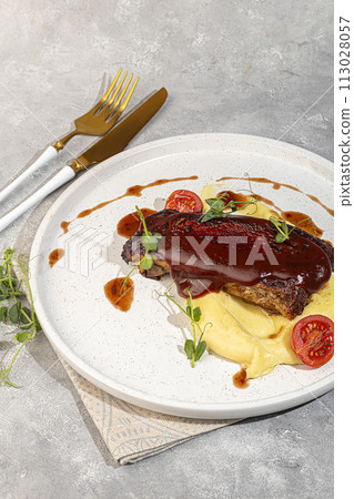 Beef on the bone with mashed potatoes, topped with red sauce and cherry tomatoes. Beef on the bone with mashed potatoes, topped with red sauce and cherry tomatoes. 113028057