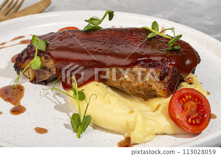 Beef on the bone with mashed potatoes, topped with red sauce and cherry tomatoes. Beef on the bone with mashed potatoes, topped with red sauce and cherry tomatoes. 113028059