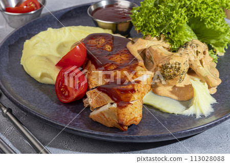 Mashed potatoes with chicken breast in red sauce with lettuce and tomato slices. Mashed potatoes with chicken breast in red sauce with lettuce and tomato slices. 113028088
