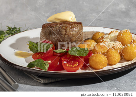 Beef medallion with potato balls and mushroom sauce, topped with a piece of butter. 113028091