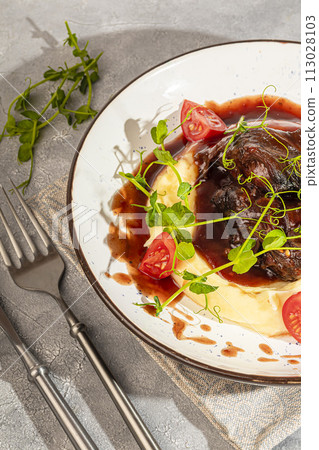 Mashed potatoes with beef in sweet and sour sauce, decorated with tomatoes and microgreens. 113028103