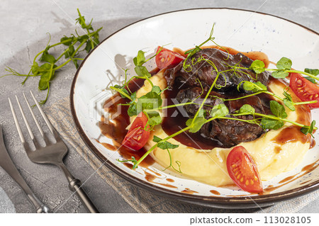 Mashed potatoes with beef in sweet and sour sauce, decorated with tomatoes and microgreens. 113028105