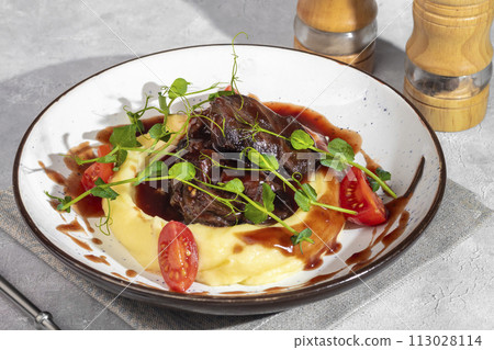 Mashed potatoes with beef in sweet and sour sauce, decorated with tomatoes and microgreens. Mashed potatoes with beef in sweet and sour sauce, decorated with tomatoes and microgreens. 113028114