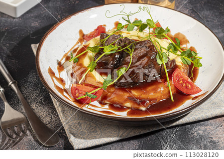 Mashed potatoes with beef in sweet and sour sauce, decorated with tomatoes and microgreens. Mashed potatoes with beef in sweet and sour sauce, decorated with tomatoes and microgreens. 113028120